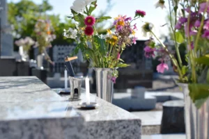 Fleurs fraîches et vases disposés sur une stèle en granit dans un cimetière